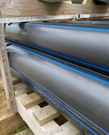 Large plastic pipes of large diameter with flanges in an open-air storage warehouse for the storage of materials and industrial equipment.