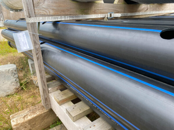 Large plastic pipes of large diameter with flanges in an open-air storage warehouse for the storage of materials and industrial equipment.